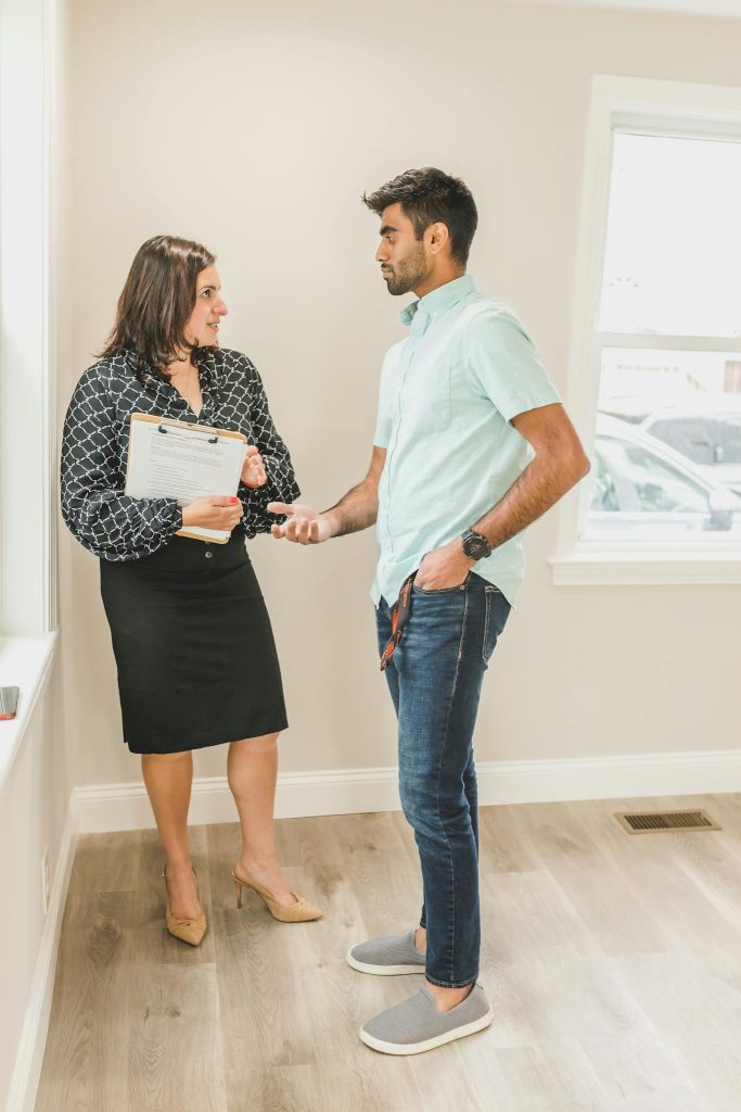 Real estate agent and client in business attire discussing a contract indoors.
